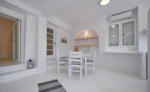 eine weiße Küche mit einem Tisch und Stühlen in der Unterkunft Fully renovated apartment in the heart of Ioulida on the island of Kea in Ioulis