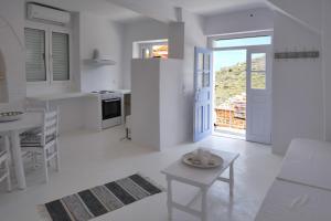 ein weißes Wohnzimmer mit einem Tisch und einer Küche in der Unterkunft Fully renovated apartment in the heart of Ioulida on the island of Kea in Ioulis