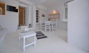 ein weißes Wohnzimmer mit einem Tisch und Stühlen in der Unterkunft Fully renovated apartment in the heart of Ioulida on the island of Kea in Ioulis