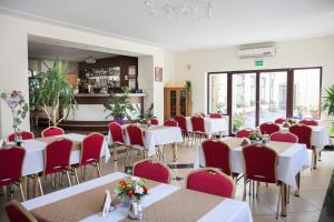 a restaurant with white tables and red chairs at Zacisze in Ulan