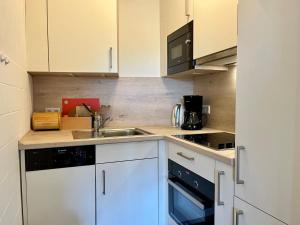 a kitchen with white cabinets and a sink at Ferienappartement Peters in Glücksburg