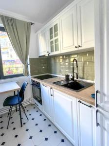 a kitchen with white cabinets and a sink and a table at FLH - Nana's apartment in Sibiu +10 photos