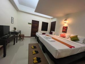 two beds in a room with a piano and a desk at Rainforest Huahin Village Hotel in Hua Hin