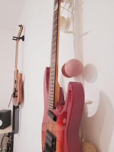 Une guitare rouge suspendue sur un mur à côté de deux autres guitares dans l'établissement Leu Repère - Location de Charme, à Saint-Leu