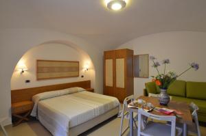 Hotel Zeus في بومباي: غرفة نوم بسرير وطاولة واريكة