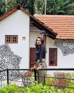 Eine Frau, die vor einem Haus steht. in der Unterkunft STAYMAKER Qexperiences Coorg in Madikeri