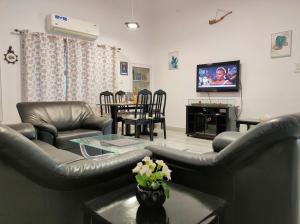 a living room with leather furniture and a tv at Homestay at Bungalow 97 Ajmer in Ajmer