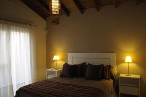 a bedroom with a bed with two lamps and a window at Lom Suites in Merlo +23 photos