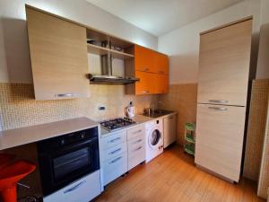 eine Küche mit orangefarbenen Schränken, einer Waschmaschine und einem Trockner in der Unterkunft Roma centro metro rebibbia in Rom