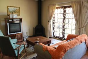 a living room with a couch and a table and a tv at Paul's Place in Dullstroom