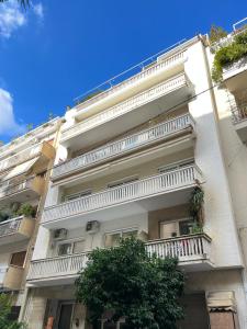 a white building with balconies and a tree in front of it at Bang in Kolonaki by Athenian Homes in Athens