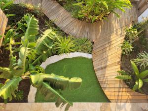 un jardín con césped verde y una pasarela de madera en Leu Repère - Location de Charme, en Saint-Leu 50 fotos más
