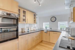 a kitchen with wooden cabinets and a clock on the wall at Fen Lane Retreat in Norwich