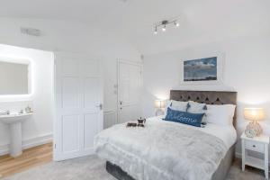 a white bedroom with a large bed and a sink at Fen Lane Retreat in Norwich