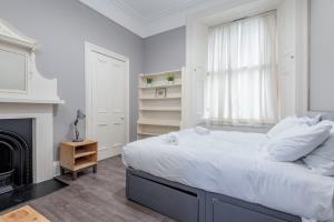 a white bedroom with a large bed and a fireplace at Queen's Gardens Apartment - 2 Bed - Central in St. Andrews
