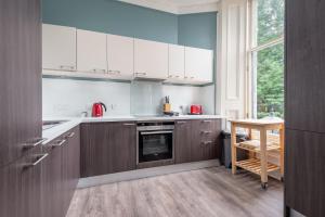 a kitchen with white cabinets and a table in it at Queen's Gardens Apartment - 2 Bed - Central in St. Andrews