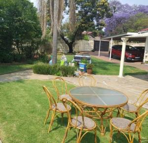 a glass table and chairs in a yard at Emma's BNB in Kempton Park