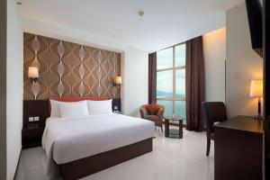 a hotel room with a white bed and a desk at Best Western The Lagoon Hotel in Manado