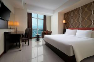 a hotel room with a large bed and a desk and a desk at Best Western The Lagoon Hotel in Manado