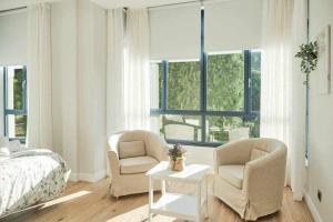 sypialnia z 2 krzesłami, łóżkiem i stołem w obiekcie CASA ROLAO Elegante Casa Familiar 10 personas w mieście Sierra de Outes