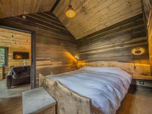 1 dormitorio con 1 cama grande en una pared de madera en Holiday home 'Be Chalet' in the heart of nature in Ferrieres en Ferrières