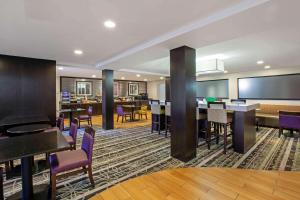 um quarto de hotel com mesas e cadeiras e um bar em La Quinta Inn & Suites by Wyndham Detroit Metro Airport em Romulus