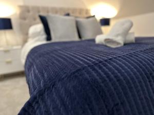 uma cama com um cobertor azul e almofadas brancas em Stunning City Centre Apartments em Cardiff