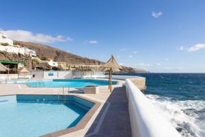 a swimming pool with the ocean in the background at Home2Book Ocean Breeze Candelaria, Terrace & Pool in Candelaria