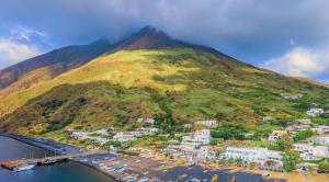 a mountain with a town next to a body of water at Hotel Ossidiana Stromboli Center in Stromboli