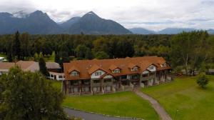 einen Luftblick auf ein großes Haus mit Bergen in der Unterkunft Hotel Pucon Green Park in Pucón