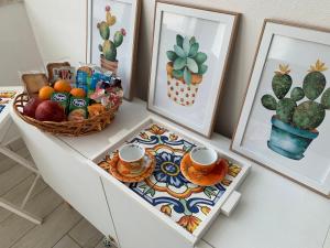 une table avec une corbeille de fruits et une corbeille de tasses et d'images dans l'établissement Albero di giada, à Massafra
