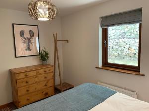 a bedroom with a bed and a dresser and a window at White Lodge - Coast Hideaways in Mawgan Porth