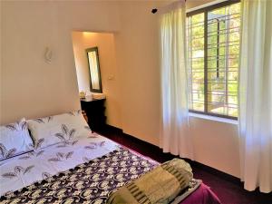 een slaapkamer met een bed en een raam bij Bella Beach Villa in Mararikulam