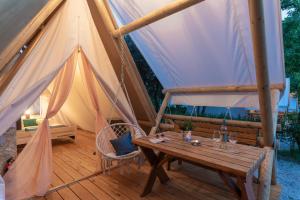 uma tenda com uma mesa de madeira e um banco em Eco glamping- FKK Nudist Camping Solaris em Porec