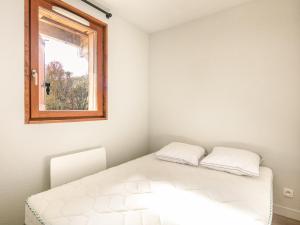 ein weißes Bett in einem Zimmer mit Fenster in der Unterkunft Les Ecureuils- 10- Appart renove- 6 pers in Saint-Sorlin-dʼArves