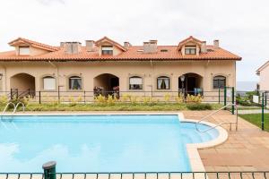 a villa with a swimming pool in front of a house at Casa de Las Flores - Apartamento con jardín privado frente a la Playa de Comillas in Comillas