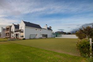 a large white house with a large green lawn at Strand Beach Lodge in Strand