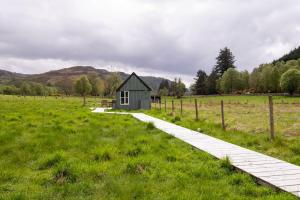 a small house in a field with a walkway at The Field House in Fort Augustus