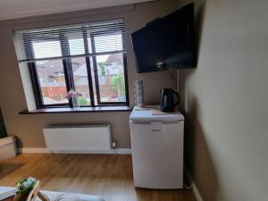 a room with a refrigerator and a flat screen tv at Spacious house City skyline and mountain views close too belfast centre and airports free parking in Belfast