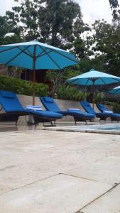 a row of blue lounge chairs with umbrellas at Light Blue Villa in Tepus