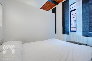 una camera bianca con un letto e una finestra di Loft White by LookAp a Łódź