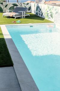 a swimming pool in the grass with a bench next to it at Villa Macaronesia in Adeje