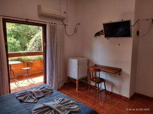 a bedroom with a bed and a television and a table at Solar das Canoas Prumirim in Ubatuba