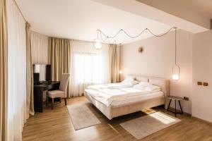 1 dormitorio con cama blanca, escritorio y silla en Villa V, en Brasov
