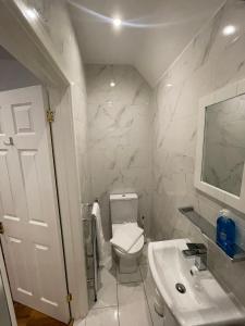 a white bathroom with a toilet and a sink at Oakhurst Gatwick B&B in Crawley