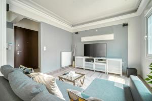 a living room with a blue couch and a tv at Charming Contemporary 2 bedroom apartment in Athens