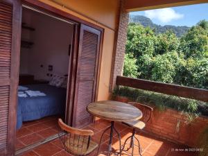 una mesa pequeña y sillas en un balcón con cama en Solar das Canoas Prumirim en Ubatuba