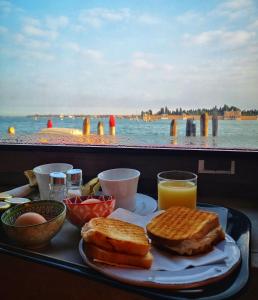 ヴェネツィアにあるHotel Vecellio Venice on the Lagoonのトースト、卵、オレンジジュースを添えた食品トレイ