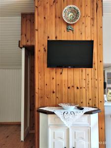 a tv on a wooden wall with a table at Σοφίτα Μαρτά in Kalamos
