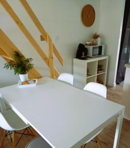 Biały stół i krzesła w pokoju z kuchenką mikrofalową w obiekcie "Studiocaroline44", entre la ville et la mer, Parking, Wifi, terrasse privé, cuisine, moins de 15min aéroport w mieście Bouaye